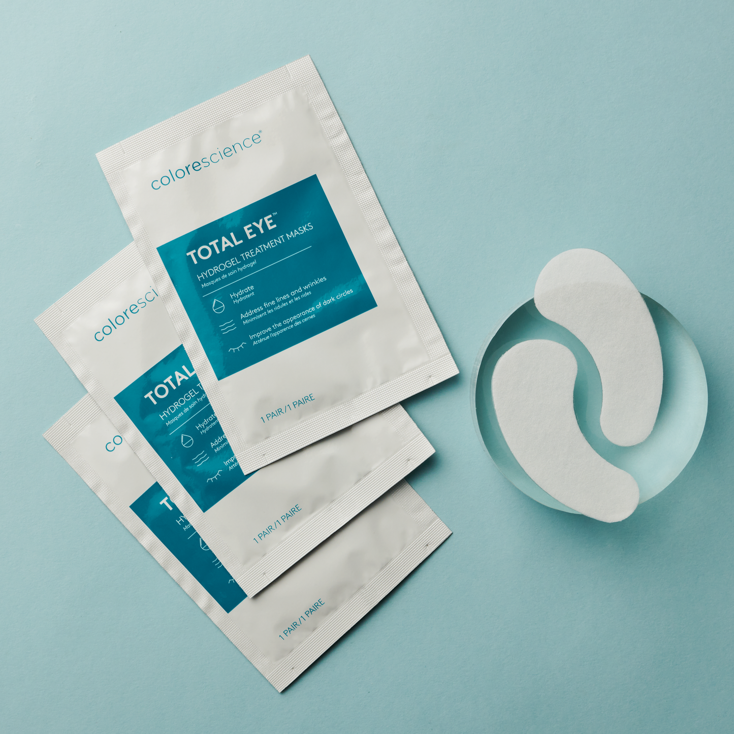 Three white sachet packets of total eye hydrogel treatment masks with eye masks next to it