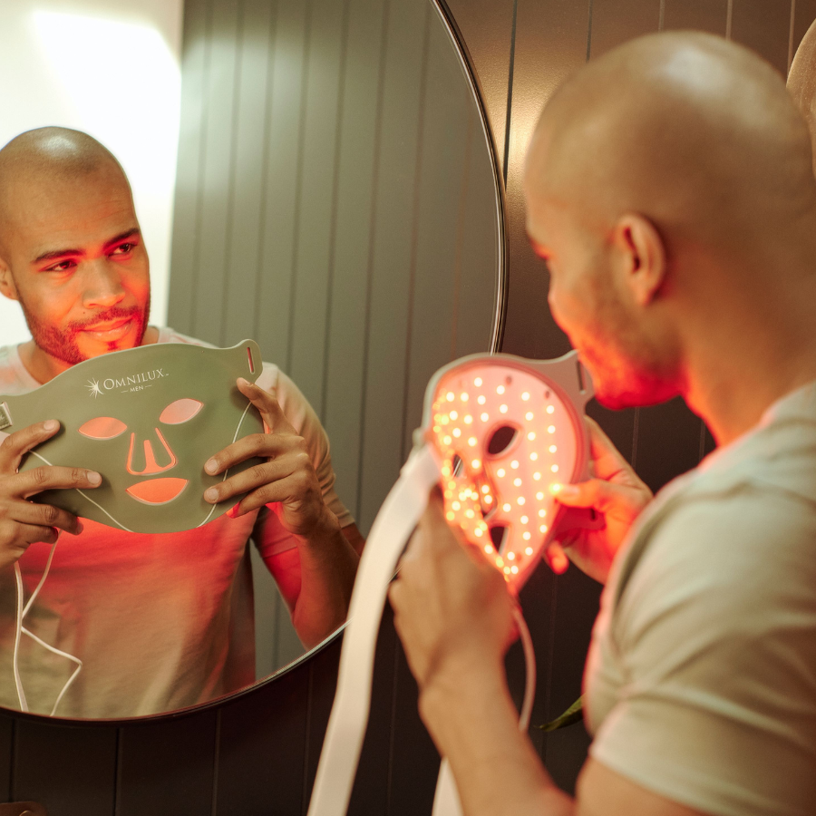 Man in front of mirror about to put on omnilux men's face mask