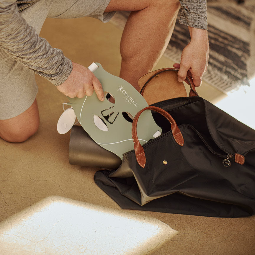 Man kneeling in front of gym bag putting omnilux men's face mask into it